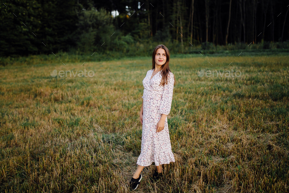 Young woman with beautiful hair posing in field at sunset. Fashion ...