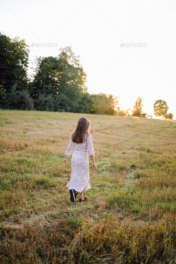 Young woman with beautiful hair posing in field at sunset. Fashion ...
