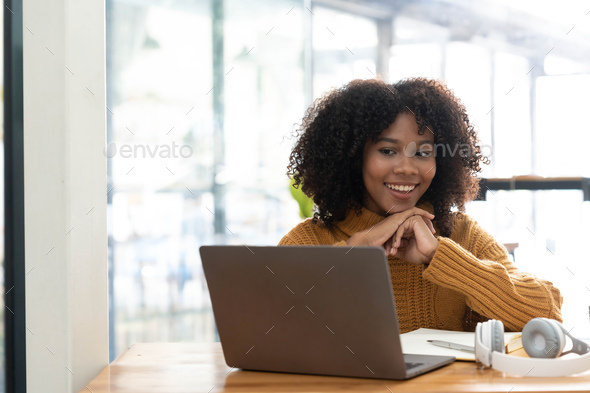 Photo of cheerful joyful mixed-race woman in yellow shirt smiling work on laptop talk speak video - Stock Photo - Images