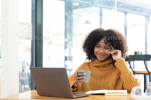 Photo of cheerful joyful mixed-race woman in yellow shirt smiling work on laptop talk speak video - Stock Photo - Images