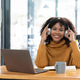 Photo of cheerful joyful mixed-race woman in yellow shirt smiling work on laptop talk speak video - PhotoDune Item for Sale