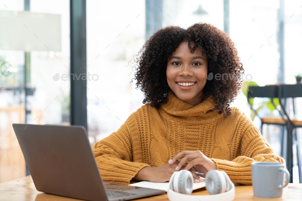 Photo of cheerful joyful mixed-race woman in yellow shirt smiling work on laptop talk speak video - Stock Photo - Images