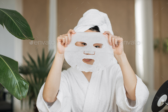 Attractive young asian lady holding in hands cotton mask in front of her face