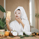 Close up portrait of happy asian woman blogger holding phone applying white cotton mask sheet - PhotoDune Item for Sale