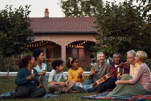 Happy multi-ethnic extended family enjoying in sounds of acoustic music in the backyard.
