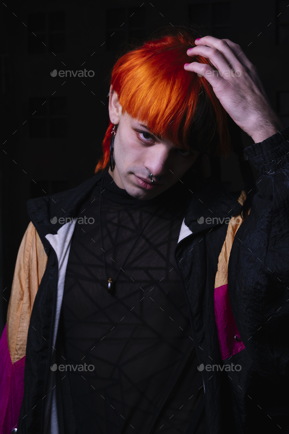 Portrait with black background of a young man with orange painted hair. - Stock Photo - Images