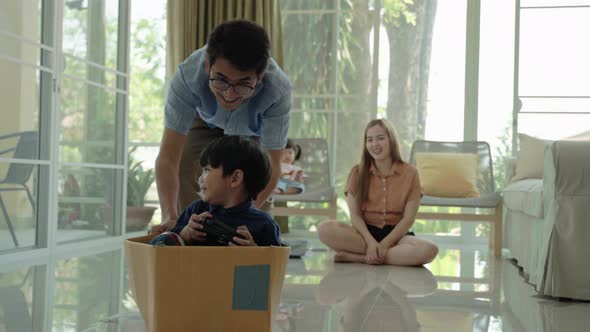 Asian family playing with a box. Together having fun inside the house
