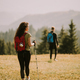 Smiling couple walking with backpacks over green hills - PhotoDune Item for Sale