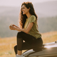 Young woman relaxing on a terrain vehicle hood at countryside - PhotoDune Item for Sale