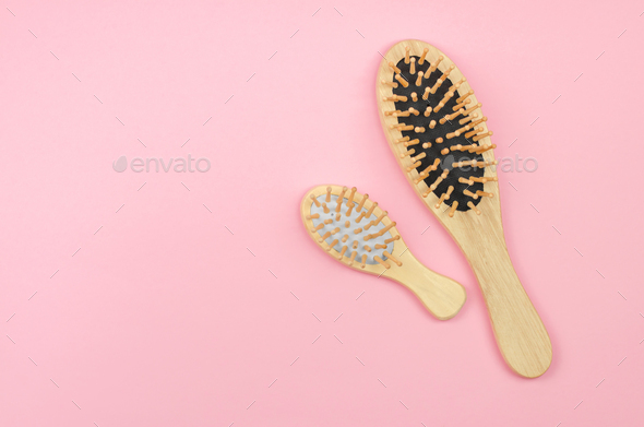 Two wooden hairbrushes on a pink background with place for text. Hair care with natural accessories