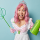Happy surprised woman with pink hair holds carpet beater and bottle of chemical detergent does house - PhotoDune Item for Sale