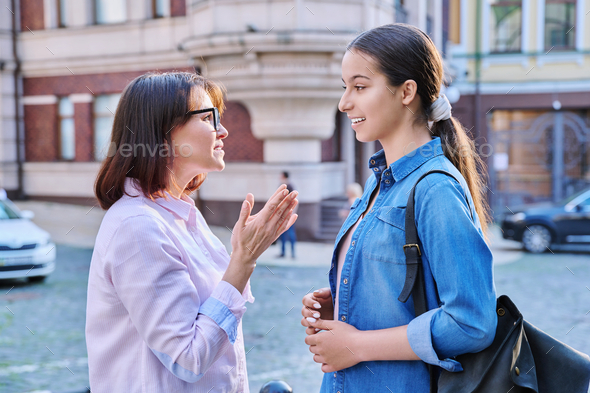 Talking mom and teenage daughter outdoors, on city street - Stock Photo - Images