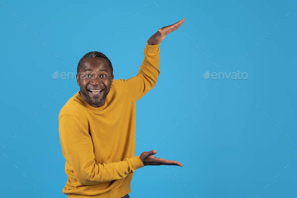 Excited african american man holding something invisible in his hands - Stock Photo - Images