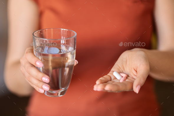 Unrecognizable Woman Holding Glass Of Water And Pile Of Pills In Hand - Stock Photo - Images