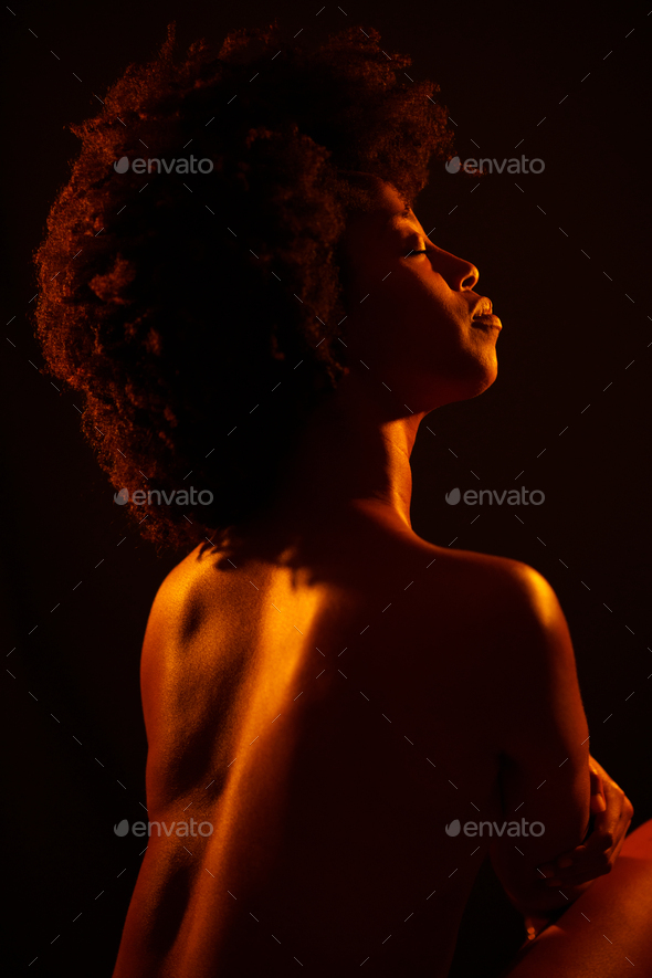 Nude black female under orange light