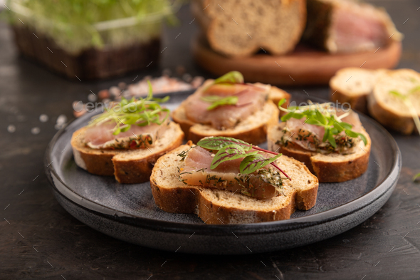 Bread sandwiches with jerky salted meat, sorrel and cilantro microgreen on black. selective focus. - Stock Photo - Images