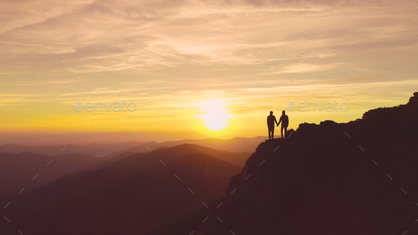 The two people standing on the mountain on the beautiful sunset ...