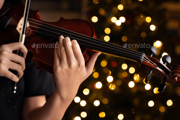 Teen playing violin in formal wear on christmas background - Stock Photo - Images