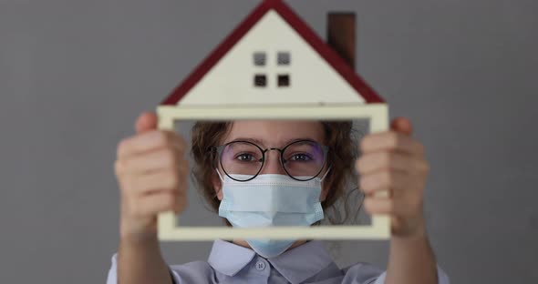 Businesswoman  wearing medical mask showing model of house in hands