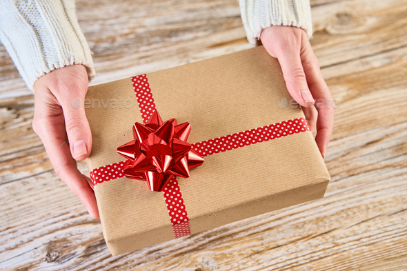 Female hands holfing festive gift box against wooden background - Stock Photo - Images