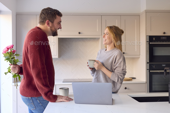 Couple At Home Looking At Laptop On Counter In Kitchen Together - Stock Photo - Images