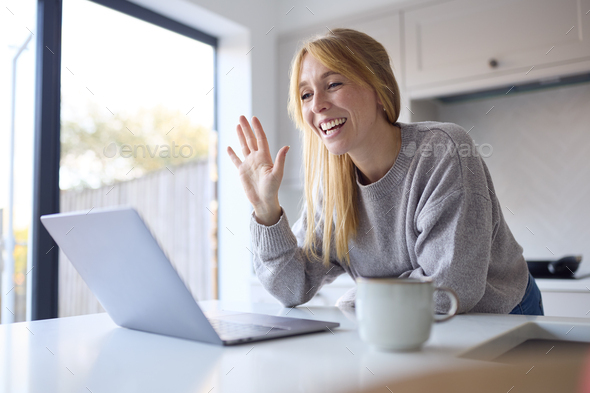 Woman At Home Making Video Call On Laptop On Counter In Kitchen Together