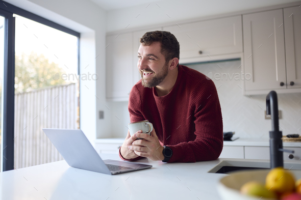 Man At Home Working On Laptop On Counter In Kitchen - Stock Photo - Images