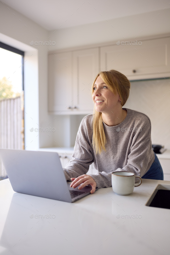 Woman At Home Working On Laptop On Counter In Kitchen - Stock Photo - Images
