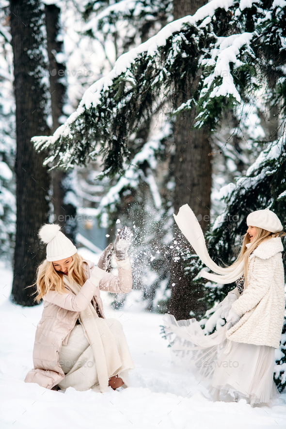 Handsome mother and daughter are having fun outdoor in winter time. Playing with snow in forest  - Stock Photo - Images