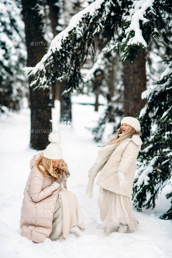 Handsome mother and daughter are having fun outdoor in winter time. Playing with snow in forest - Stock Photo - Images