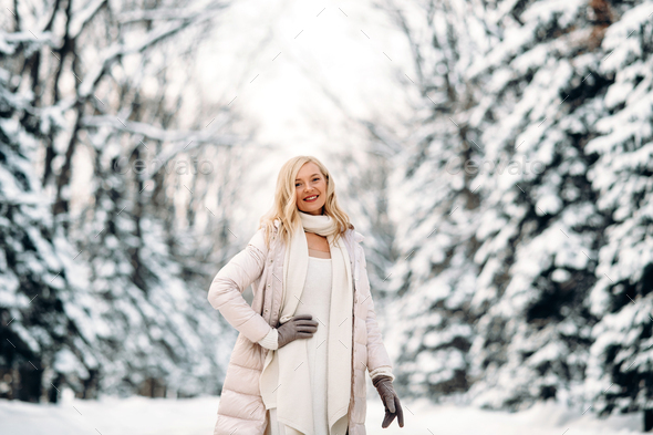 Fashion young smiling blonde woman in winter. Standing among snowy trees in winter forest. - Stock Photo - Images