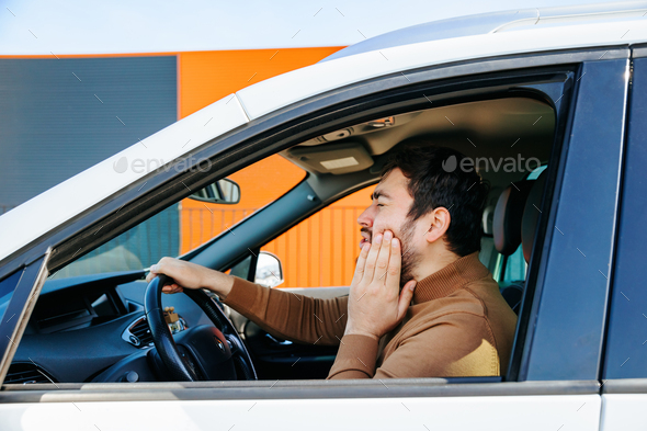 Caucasian disturbed bearded chauffeur man he has toothache in the interior of a car.