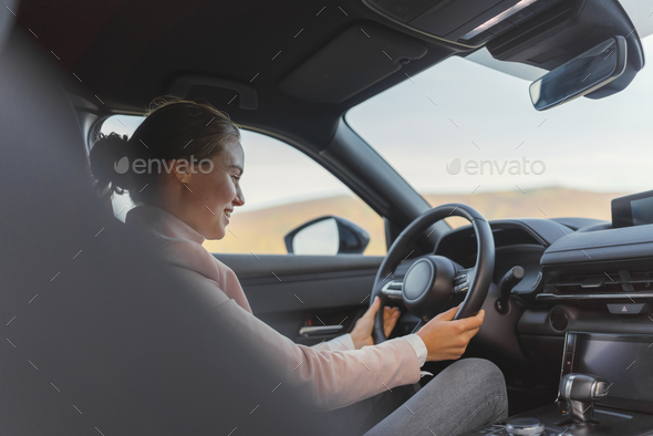 Excited young woman driving her electric car. - Stock Photo - Images