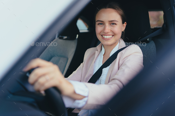 Excited young woman sitting in her car, prepared for driving. - Stock Photo - Images