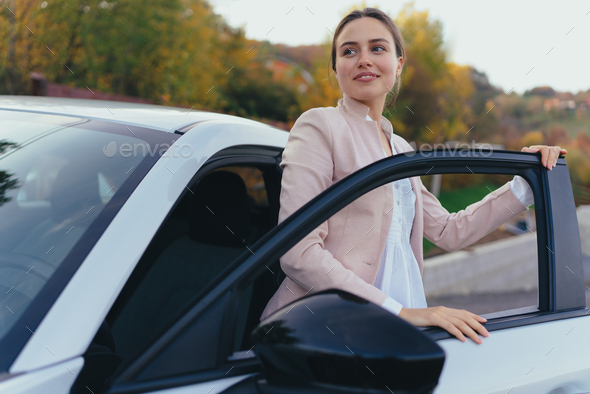 Happy young woman getting out of her car. - Stock Photo - Images