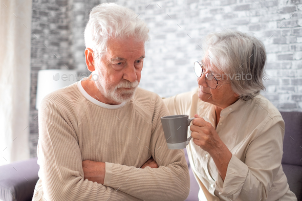 Old worried senior woman comforting her depressed, mental ill husband, unhappy elderly man