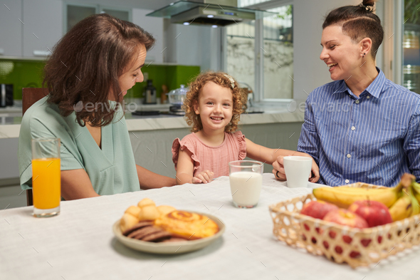 Girl and Mothers Sitting at Breakfast Table - Stock Photo - Images