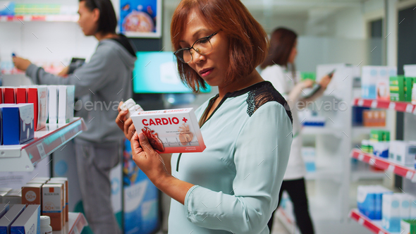 Pharmacy client reading cardiology drugs boxes on shelves
