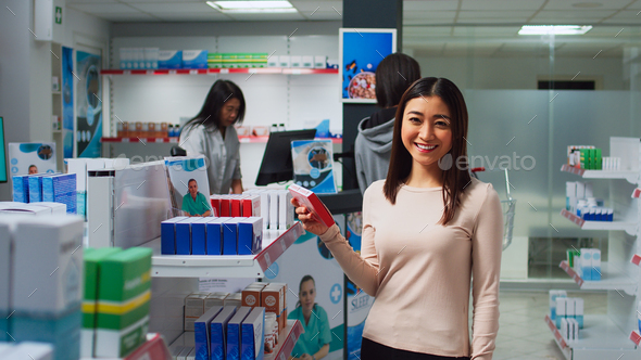 Asian client checking medicine boxes on drugstore shelves