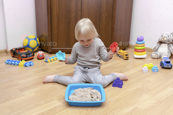 child boy playing at home in sensory box with kinetic sand