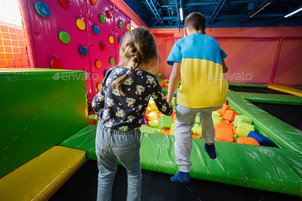 Brother with sister playing at indoor play center playground , jumping in color cubes pool. - Stock Photo - Images