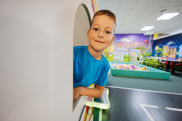 Boy playing at indoor play center playground, looking from window. - Stock Photo - Images