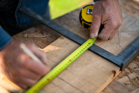 Close-up of handyman measuring a board, outside in garden. - Stock Photo - Images