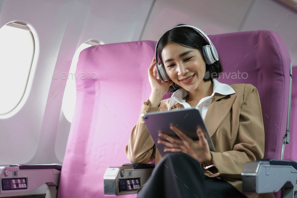 Young caucasian smiling female enjoying her comfortable flight while sitting in airplane cabin - Stock Photo - Images