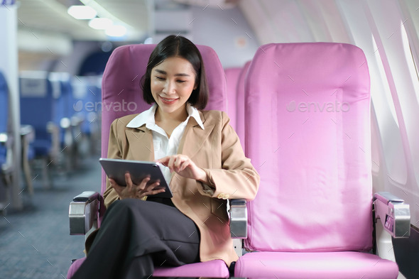 Attractive caucasian female passenger of airplane sitting in comfortable seat while working at - Stock Photo - Images