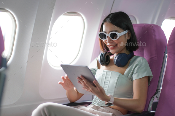 Travel tourism with modern technology and air flights concept, woman sitting in plane with modern - Stock Photo - Images