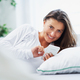 Young brunet woman with smartphone on the bed - PhotoDune Item for Sale