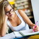Happy young female studying and preparing for exam in college library. Education people concept - PhotoDune Item for Sale