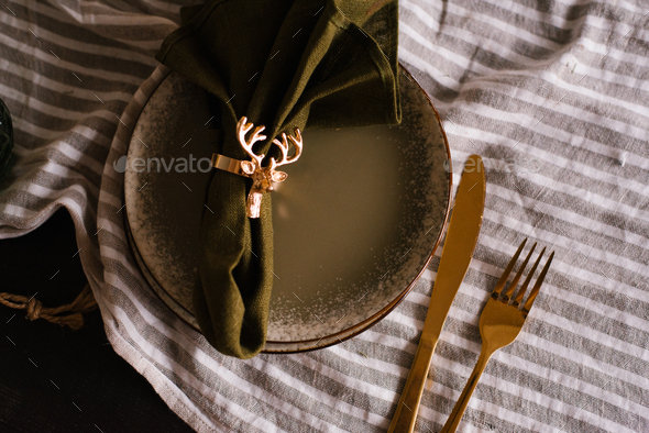 Christmas table setting with an elegant gold napkin ring on a plate