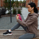 Thirsty fitness woman in earphones sitting on the bench and opening bottle  - PhotoDune Item for Sale